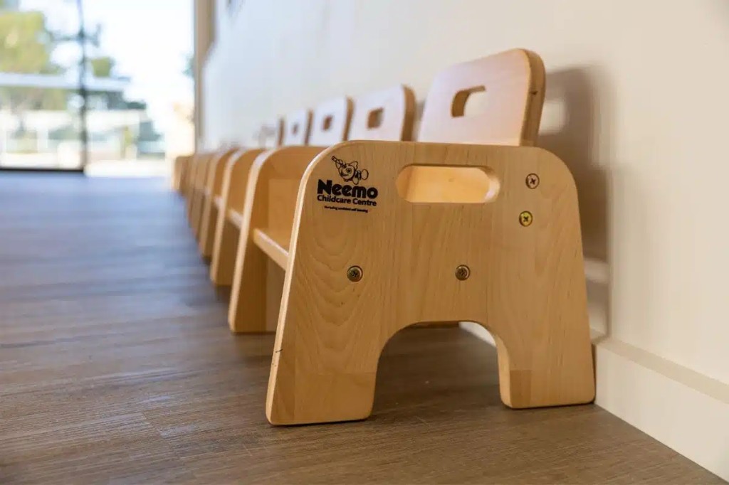 Custom branded wooden children's chairs lined up in a childcare centre