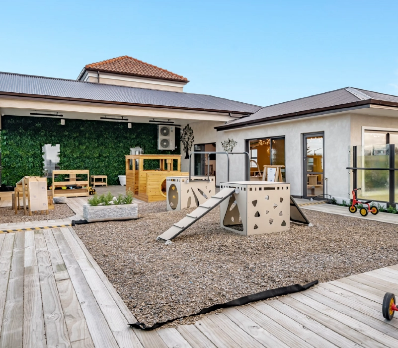 Courtyard deck with gravel play zone, modular climbing structures, and vertical planting wall