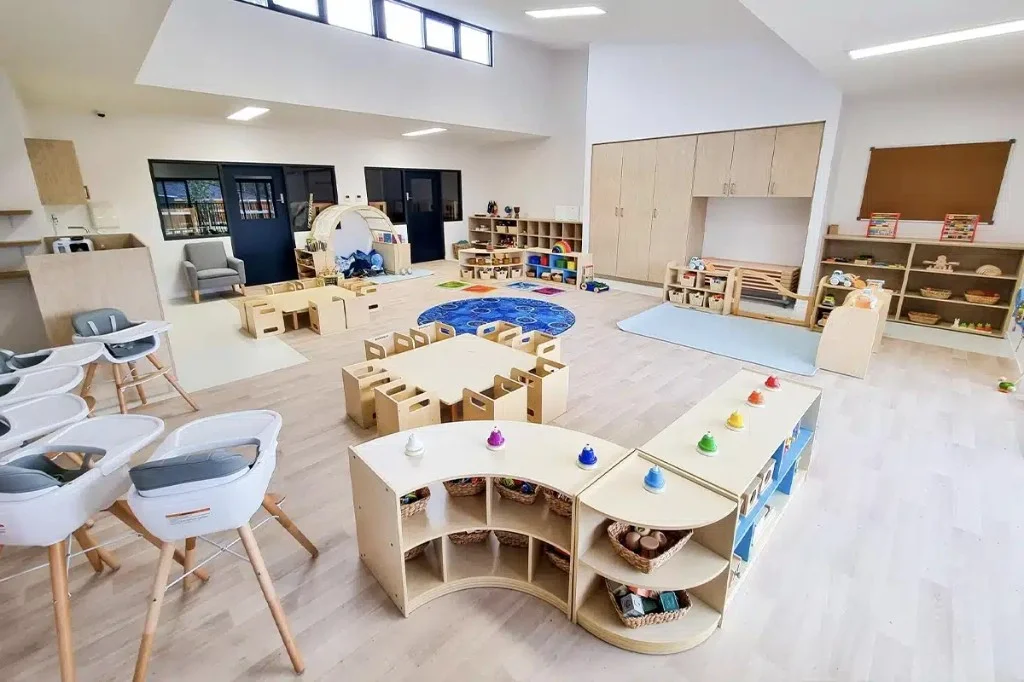 Open early learning space with natural wood furniture, zoned play areas, and child-height open shelving