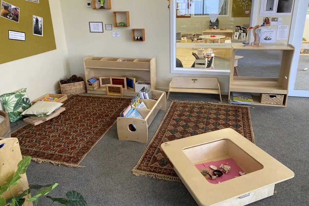 Early learning corner with sensory table, low book storage, and patterned area rugs